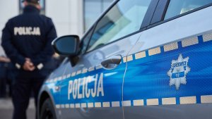 Policjant stoi obok radiowozu