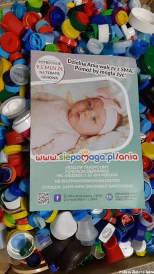 Na nakrętkach leży plakat propagujący zbiórkę na rzecz chorego dziecka
