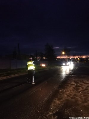 Policjant w nocy zatrzymuje do kontroli pojazd.