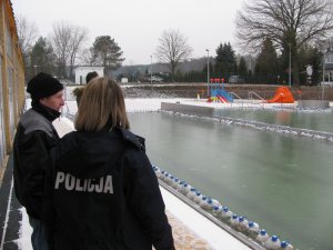 Policjantka rozmawia z mężczyzną przy zamarzniętym basenie