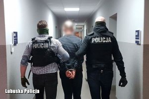 Policjanci prowadzą zatrzymanego w budynku Komendy