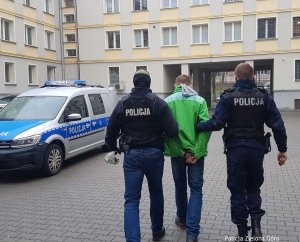 Policjanci prowadzą zatrzymanego na dziedzińcu Komendy