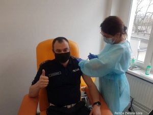 Policjant otrzymuje zastrzyk w ramię od pielęgniarki