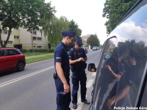 Dwóch policjantów rozmawiający z kierowcą szarego samochodu