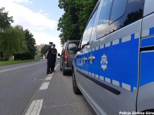 Dwóch policjantów rozmawiający z kierowcą szarego samochodu