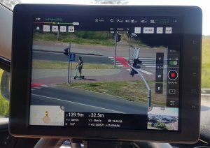 Obraz z kamery drona przedstawiający przejście dla pieszych i przejazd dla rowerzystów z sygnalizacją świetlną
