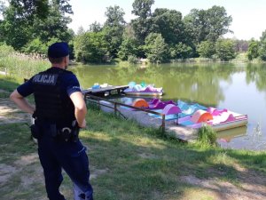 Policjant patrzący na plaże na tle rowerów wodnych