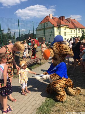 Maskotka policyjna dająca ulotkę małemu dziecku