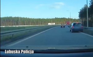 Granatowe auto marki Renault jadące połową samochodu po prawym poboczu drogi.