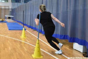 kobieta w czarnym stroju biegnąca pomiędzy słupkami