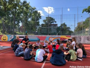 Dzieci siedzą w kółku i rozmawiają z policjantką