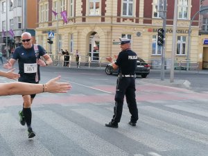 Policjant podczas biegu i policjant Ruchu Drogowego zabezpieczający trasę biegu