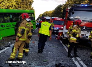 Policjant ruchu drogowego oraz strażacy na miejscu wypadku drogowego