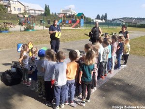 Policjantka rozmawia z dziećmi i pokazuje im znaki drogowe