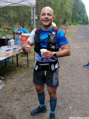 Policjant pijący wodę na jednym ze stoisk w trakcie ultramaratonu.