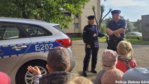 Dwójka policjantów stojąca przed grupą dzieci.