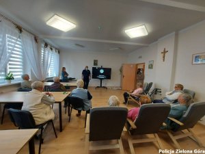 Policjantka omawia prezentacje na temat bezpieczeństwa seniorom.