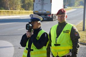 Policjantka Ruchu Drogowego i żołnierz żandarmerii wojskowej kontrolują prędkość samochodów na jednej z ulic