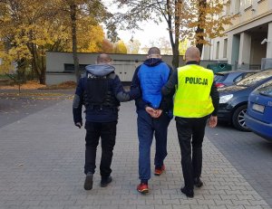 Policjanci prowadzą zatrzymanego mężczyznę