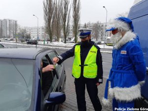 Polikołaj wraz z policjantką wręczają odblask kierowcy.