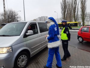 Polikołaj z policjantką idą w stronę zaparkowanego busa.