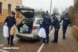 Policjanci pakują szlachetne paczki dla potrzebujących seniorów.