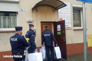 Policjanci wnoszą szlachetne paczki dla potrzebujących seniorów.