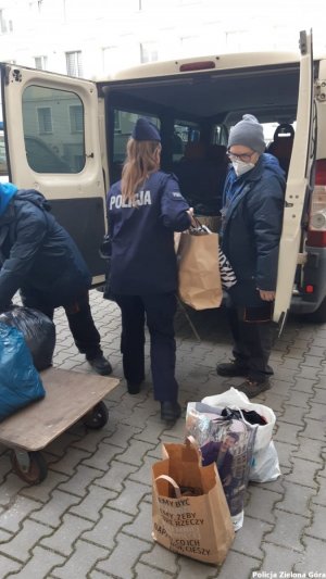 Policjanci pakują ciepłą odzież do busa.