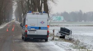 Bus policyjny stoi przy samochodzie który wypadł z drogi.