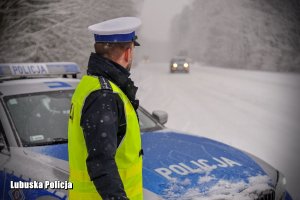 radiowóz policyjny zaparkowany obok zaśnieżonej drogi.