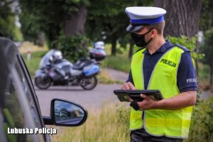 Policjant legitymuje kierowcę samochodu osobowego.