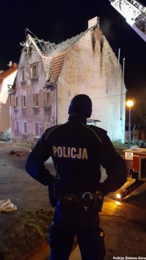 Policjant stojący przed jednym z domów w kamienicy.