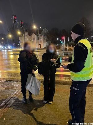 Policjant wręcza odblaski przechodniom.