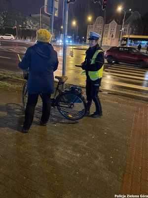 Policjantka przekazuje odblask rowerzystce.