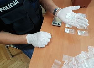 Policjant w białych rękawiczkach ważący znalezione substancje.