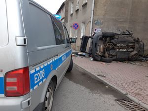Radiowóz policyjny stoi obok rozbitego samochodu.