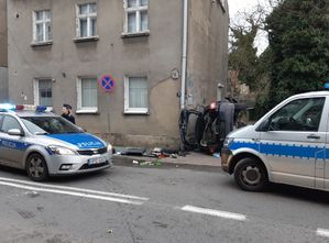 Dwa radiowozy policyjne wraz z policjantką obok rozbitego samochodu.
