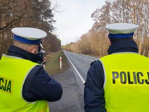 Dwójka policjantów ruchu drogowego mierzy prędkość nadjeżdżających samochodów.