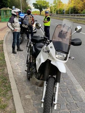 Motocykl a za nim funkcjonariusz policji wraz z właścicielem pojazdu.