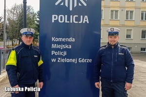 Dwaj policjanci ruchu drogowego w granatowych mundurach stojący przed napisem Komenda Miejska Policji w Zielonej Górze