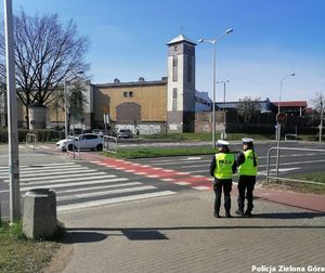 Dwójka policjantów stojąca przed pasami.