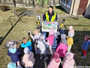 Policjantka uczy dzieci jak bezpiecznie poruszać się pasami dla pieszych.