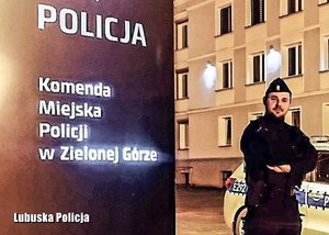 Policjant na tle napisu Komenda Miejska Policji.