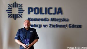 Policjant a w tle napis Komenda Miejska Policji.