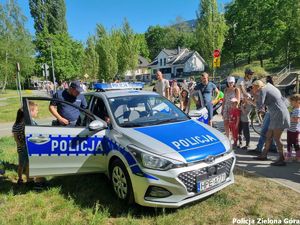 Radiowóz policyjny wraz z grupą cywili i policjantami.