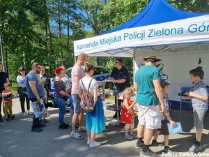 Stragan policyjny gdzie znajduje się po,policjantka i kolejka cywili do straganu.