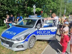 radiowóz policyjny z grupą cywili oraz policjantów.