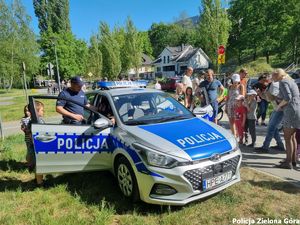 radiowóz policyjny wraz z policjantami obok oraz cywilami.