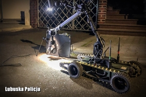 Robot trzyma przedmioty którym policjanci robią zdjęcia rentgenowskie.