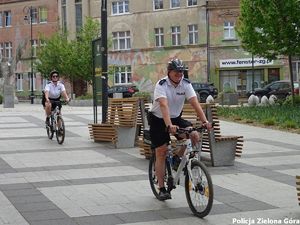 Dwójka policjantów jadąca rowerami po parku teatralnym.